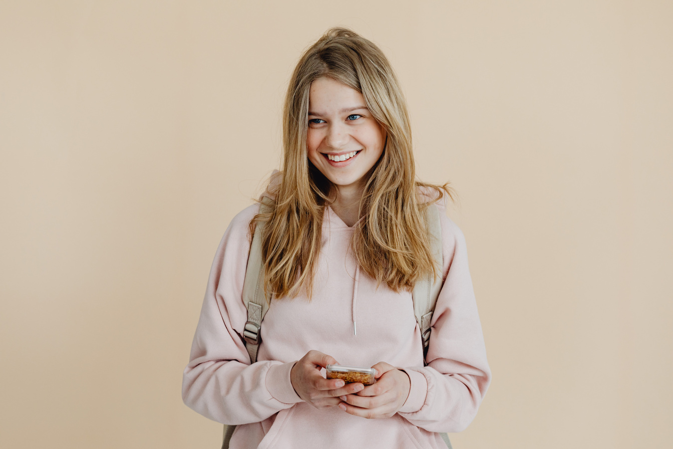 A Woman in Pink Sweater Smiling while Holding Her Mobile Phone